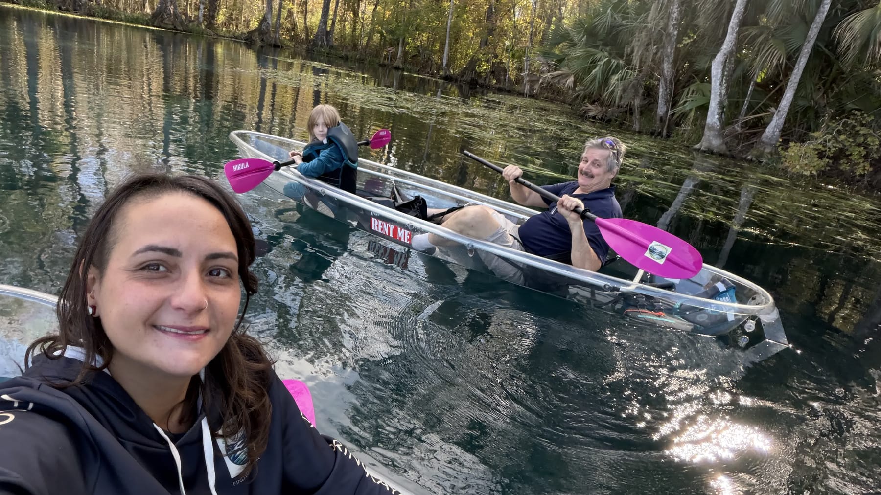 A family paddling a clear kayak on a Florida spring